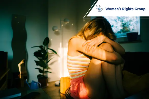 A girl sits on a couch in a dim room